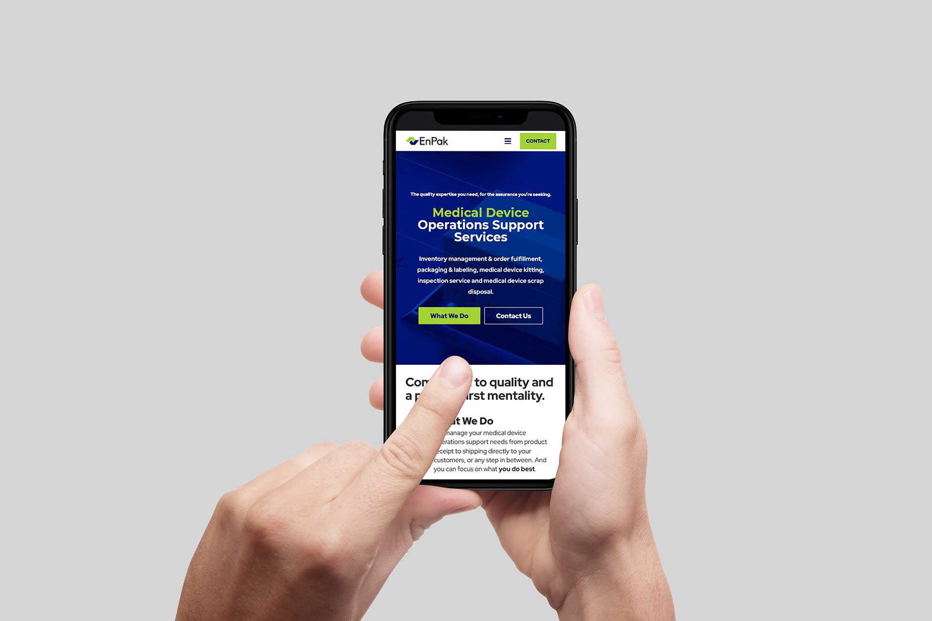 Hand holding a smartphone with EnPaks medical support services webpage.