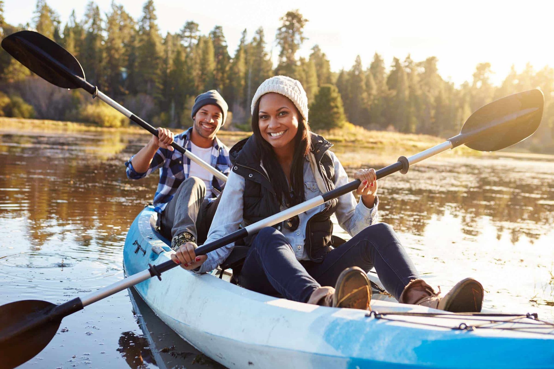 Two people kayaking on a calm Fulton County lake surrounded by trees.