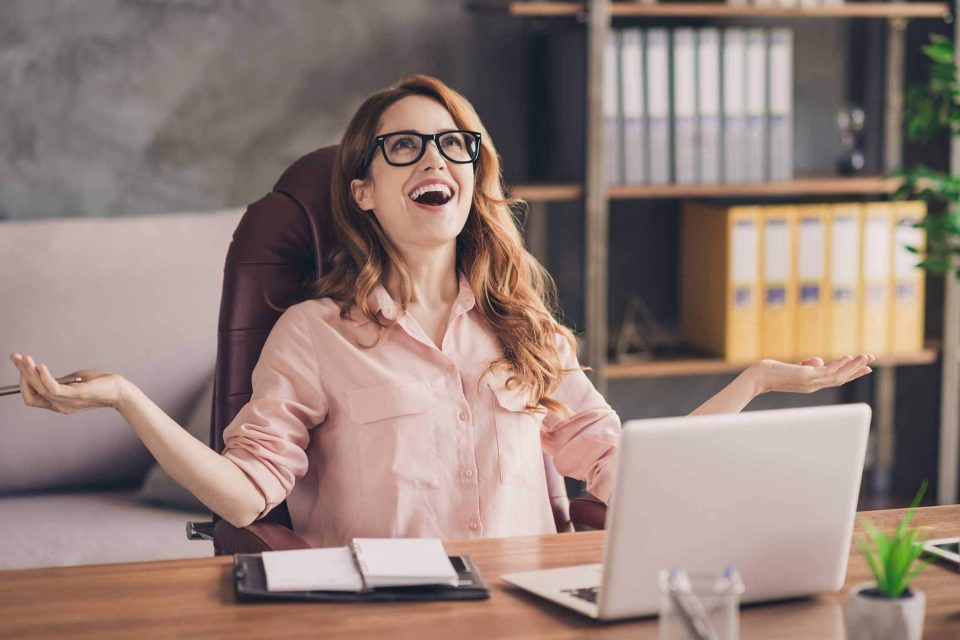Person in glasses, smiling with arms raised, celebrates website traffic.
