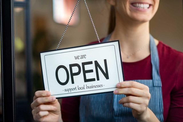 A person holds a We are open sign at Huntington County Chambers store.