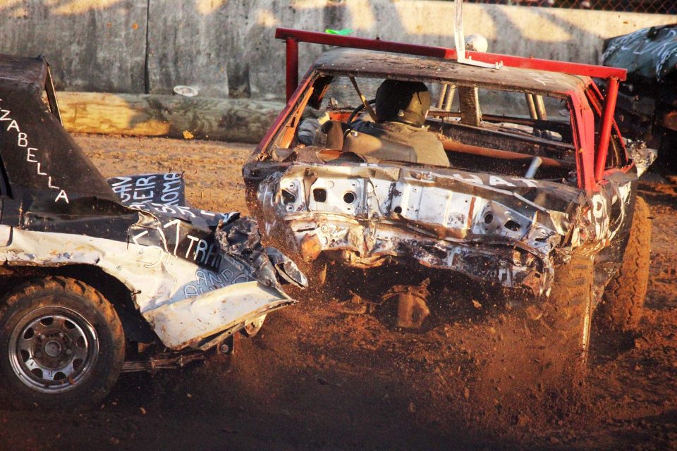 Two cars collide in an Impact Derby, kicking up a cloud of dust.