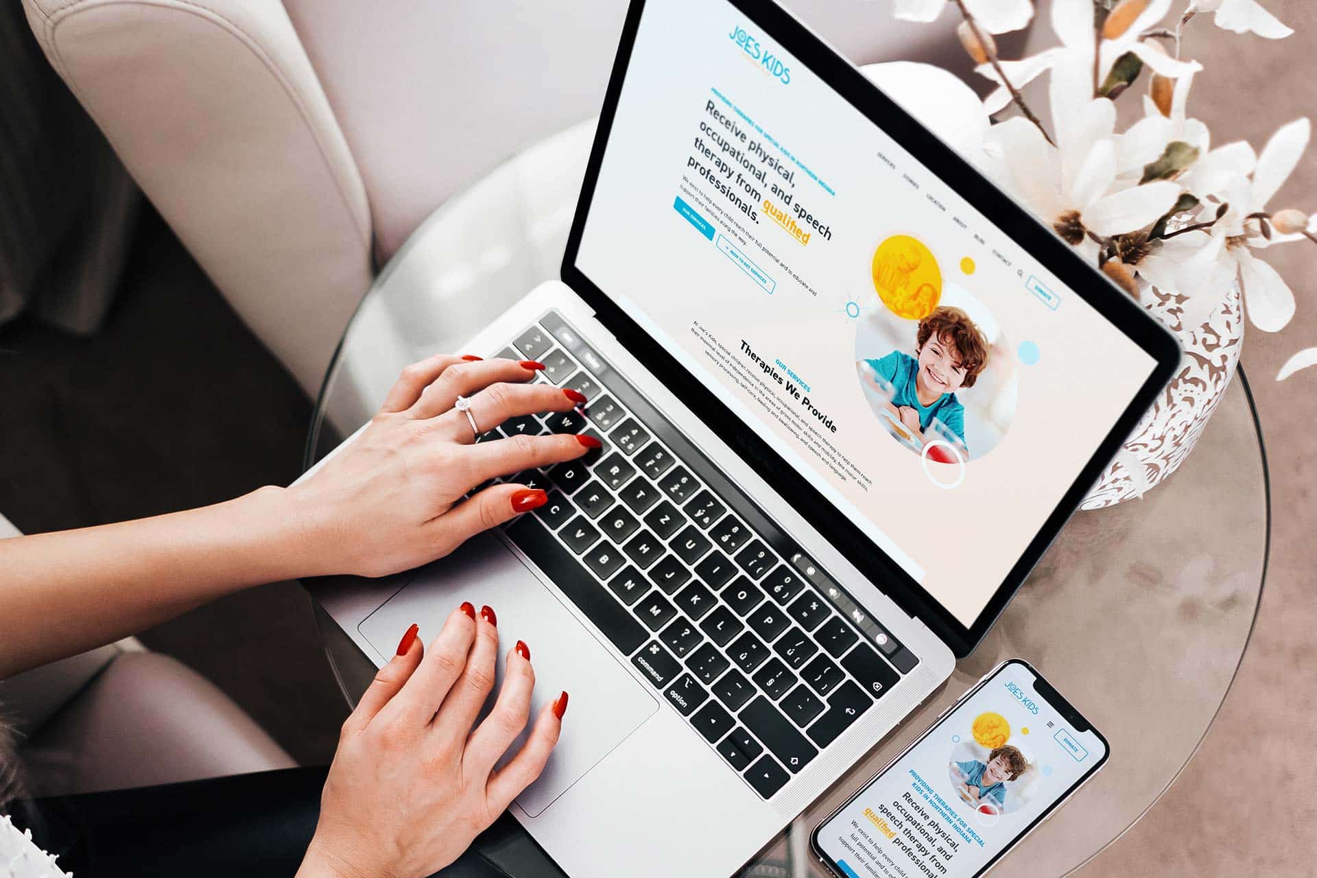 Person using a laptop with a matching phone page on the table.