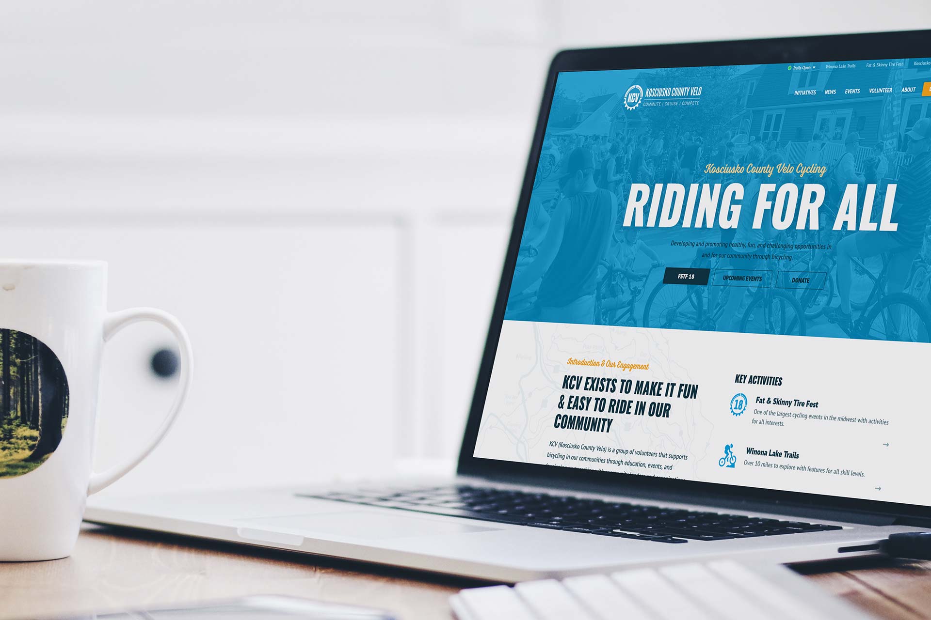 Laptop displaying a Kosciusko County Velo site next to a coffee mug.