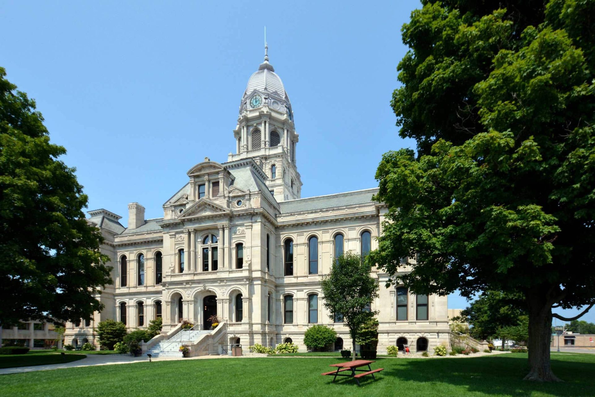 KEDCos courthouse with clock tower amidst lush green trees.