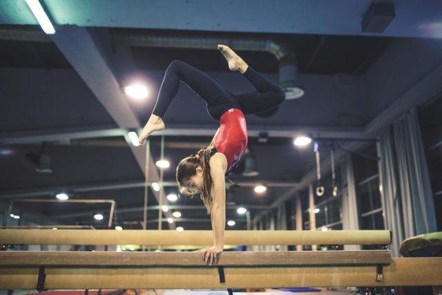 Lake City Gymnastics star in a handstand on the balance beam.