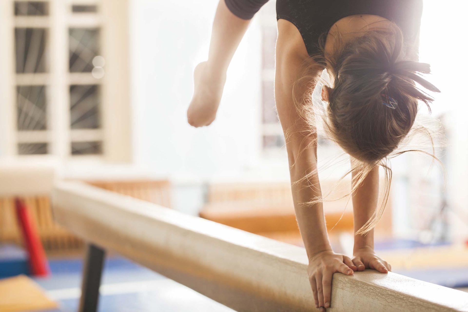 A girl from Lake City Gymnastics performs a handstand on a balance beam.
