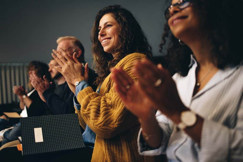 Attendees at Love Fort Wayne smile and clap in a joyful row.