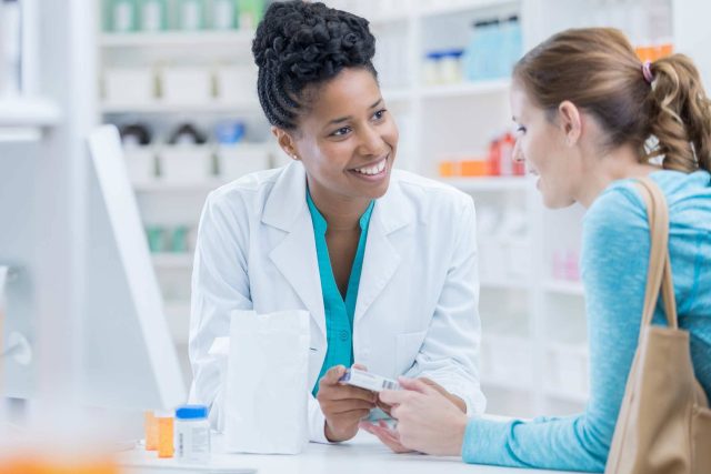Pharmacist assisting a customer at a pharmacy counter.