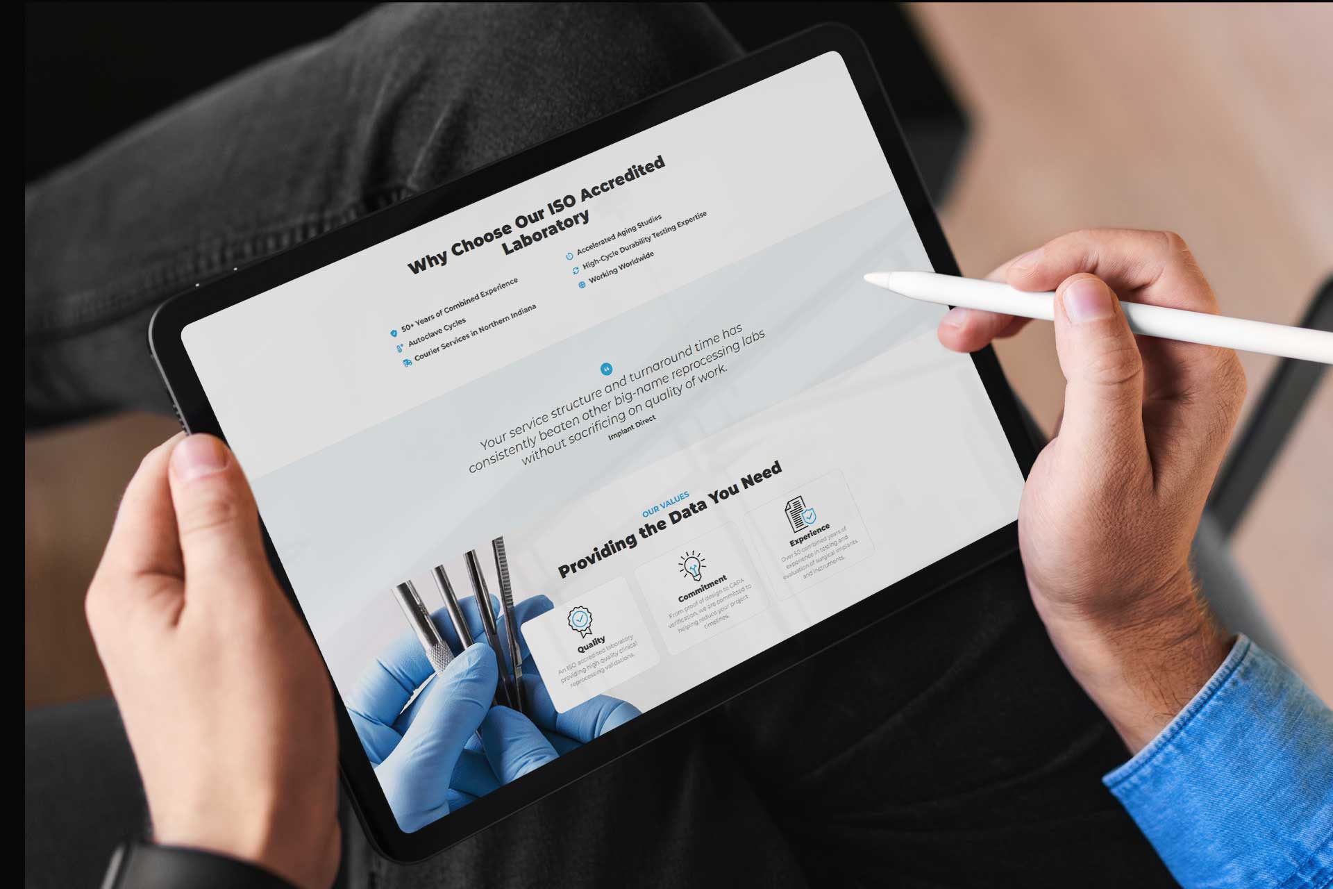 Person holding a tablet with SteriLogixs laboratory webpage displayed.