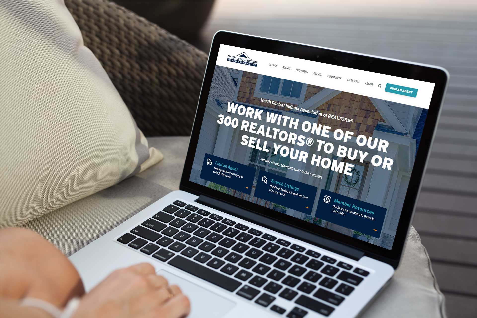 Laptop showing NCIARs real estate site on a wooden table.