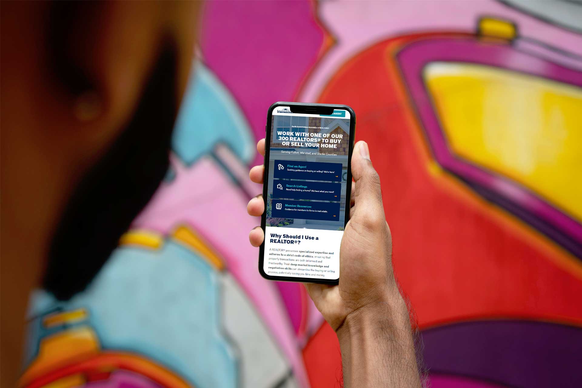 Person holding an NCIAR smartphone by vibrant graffiti.