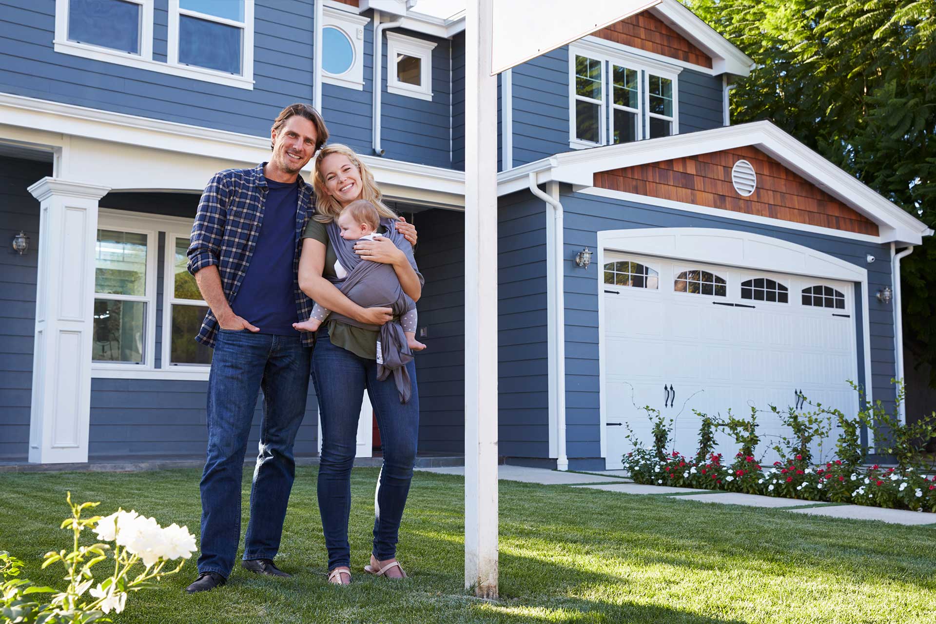 A couple with a baby beams outside their NCIAR blue house.