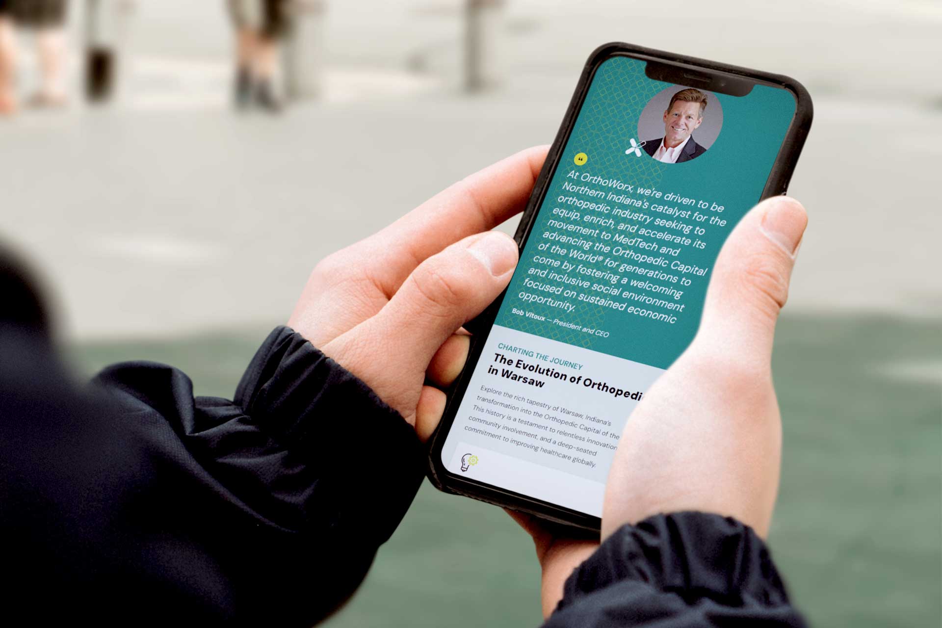 Person holding a smartphone showing the OrthoWorx medical-themed webpage.