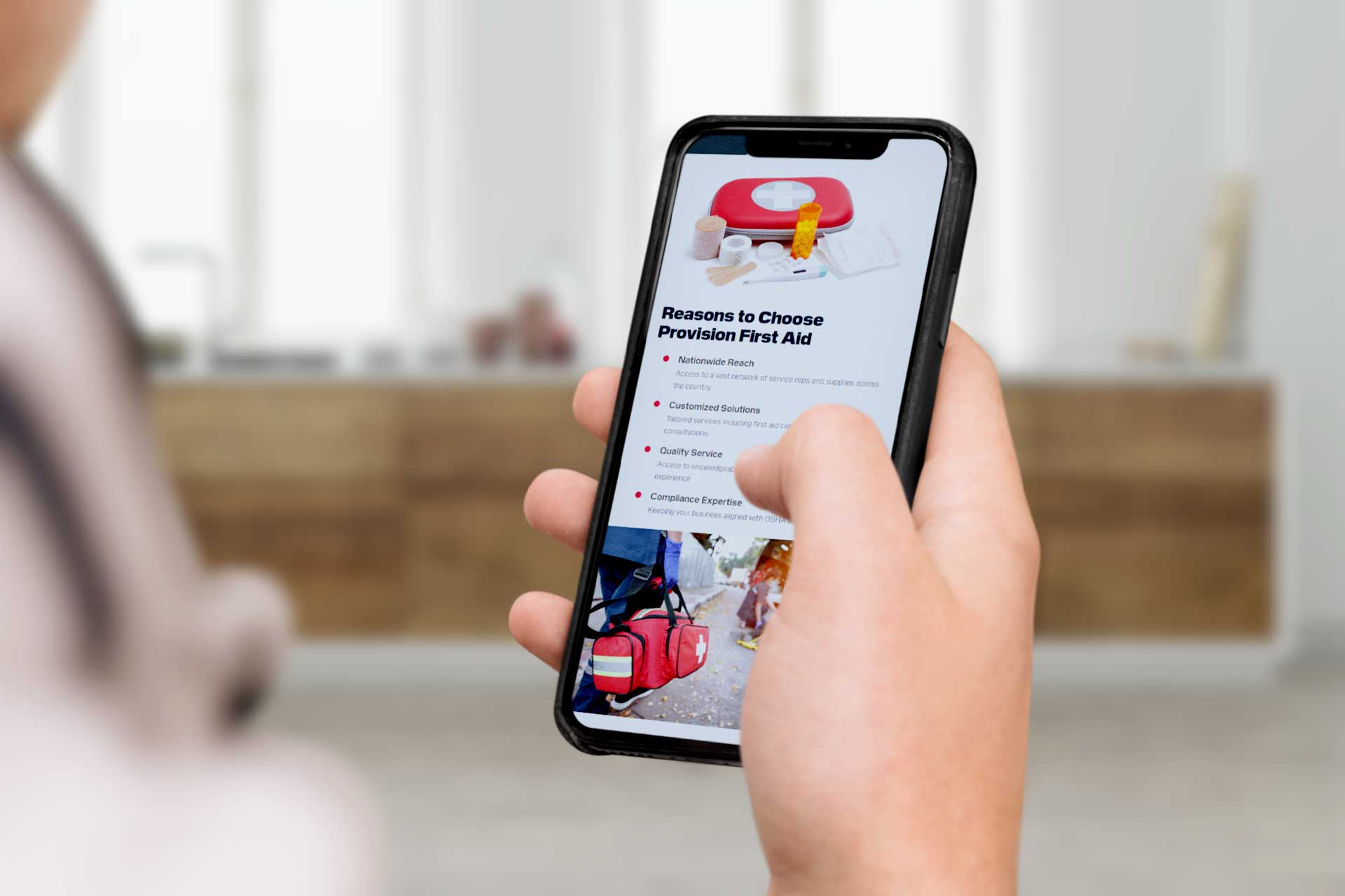 Person holding a smartphone displaying the Provision First Aid website page.