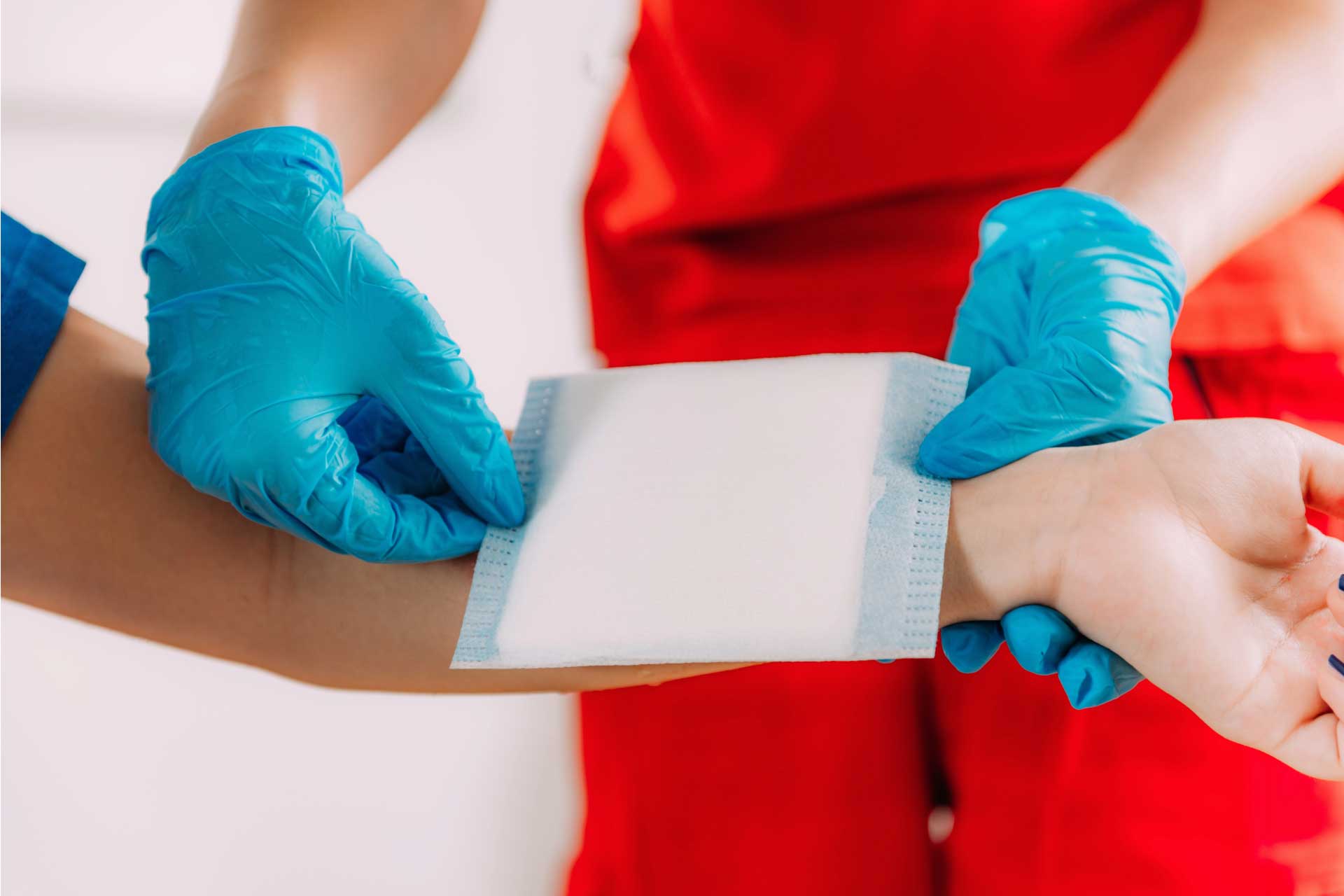 Gloved hands provision first aid, bandaging a persons wrist.