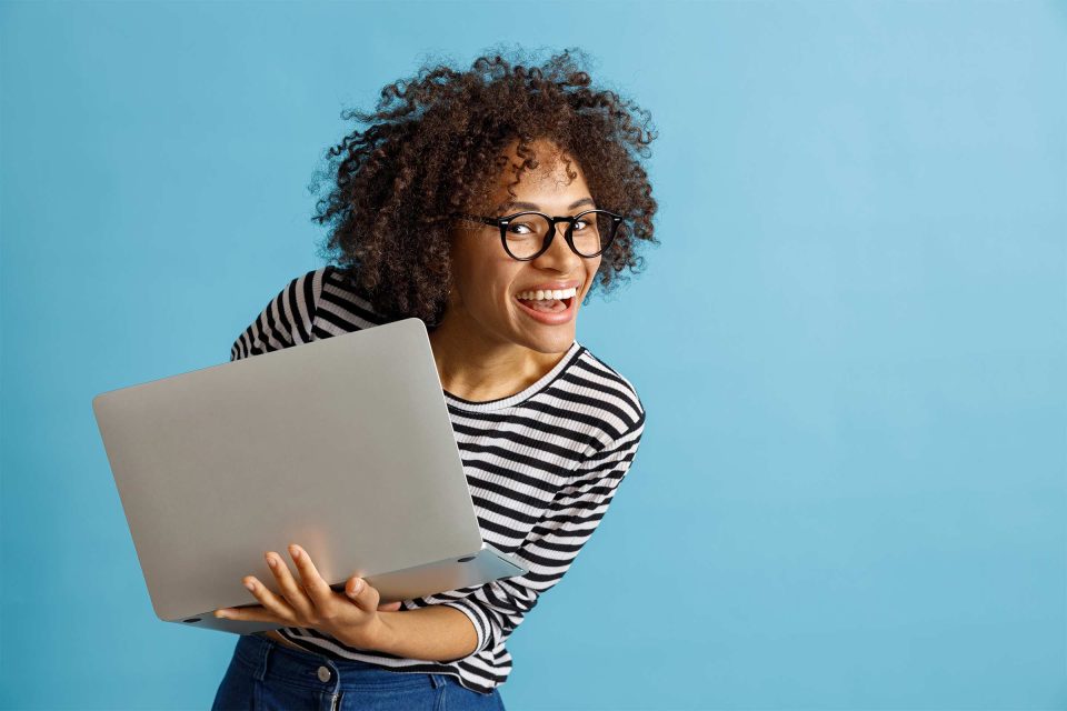 Person smiling, repurposing old blog content on a laptop against a blue background.