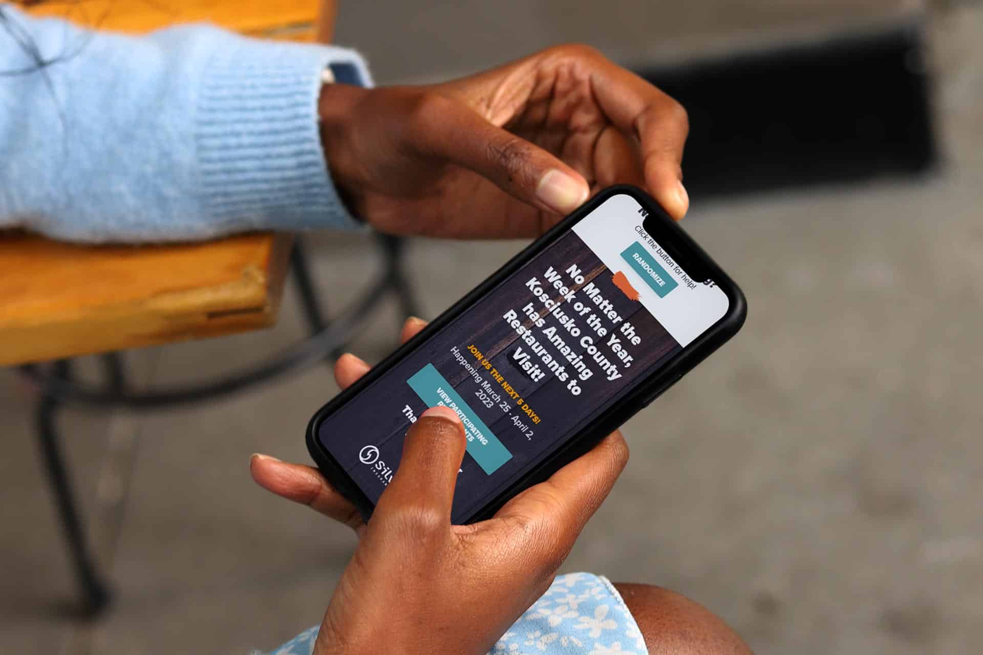 Person holding a phone displaying a website on a wooden bench.