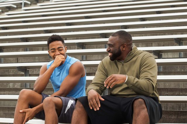 Two people on bleachers, laughing and chatting about the Shepherd Network.