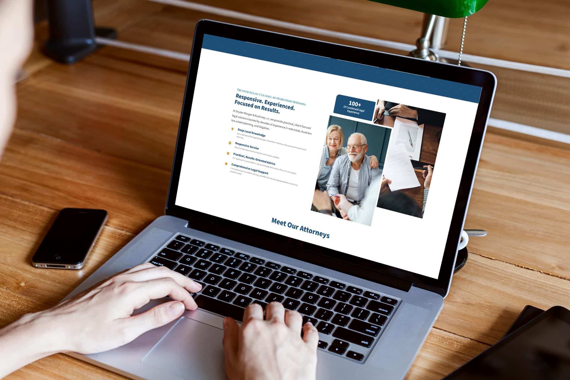 Person using a laptop displaying a professional website with attorney profiles.