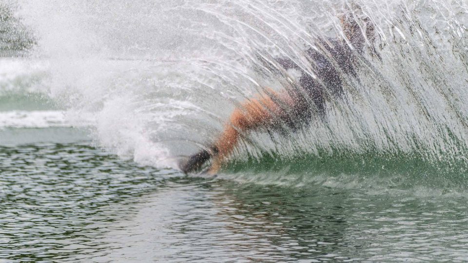 Person waterskiing near Syracuse, creating a large spray of water behind them.