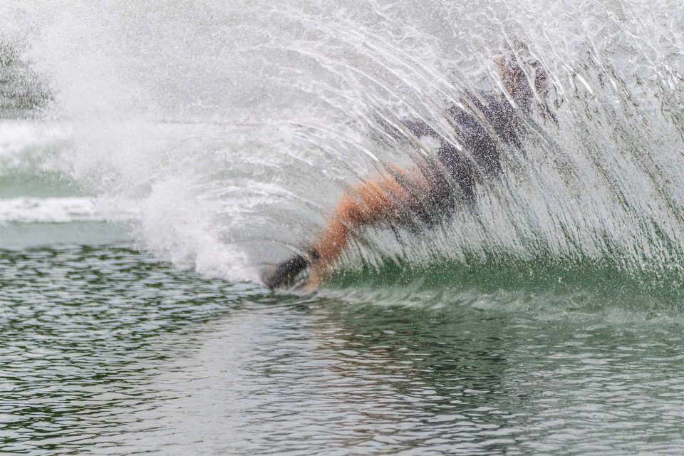 Person waterskiing near Syracuse, creating a large spray of water behind them.