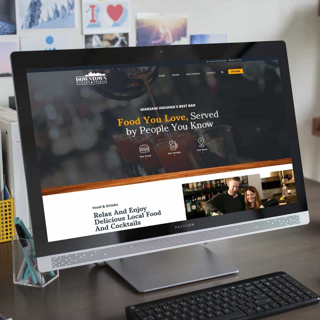 Computer monitor displaying a restaurant website on a desk.