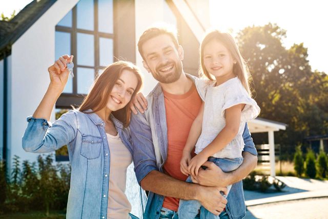 Family smiling with new keys, proud of their timber construction home.