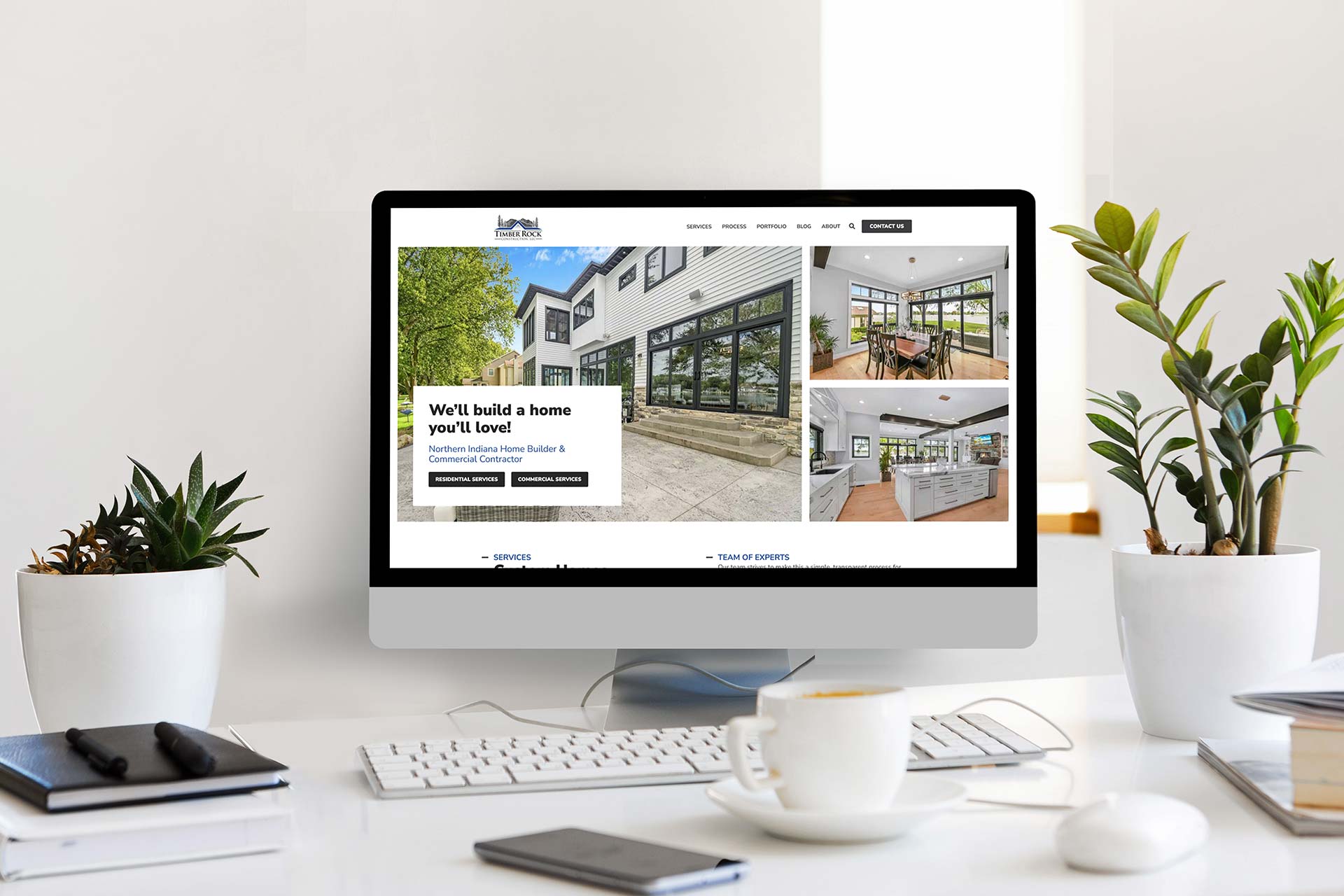 Timber-framed website on screen, plants surround the display.