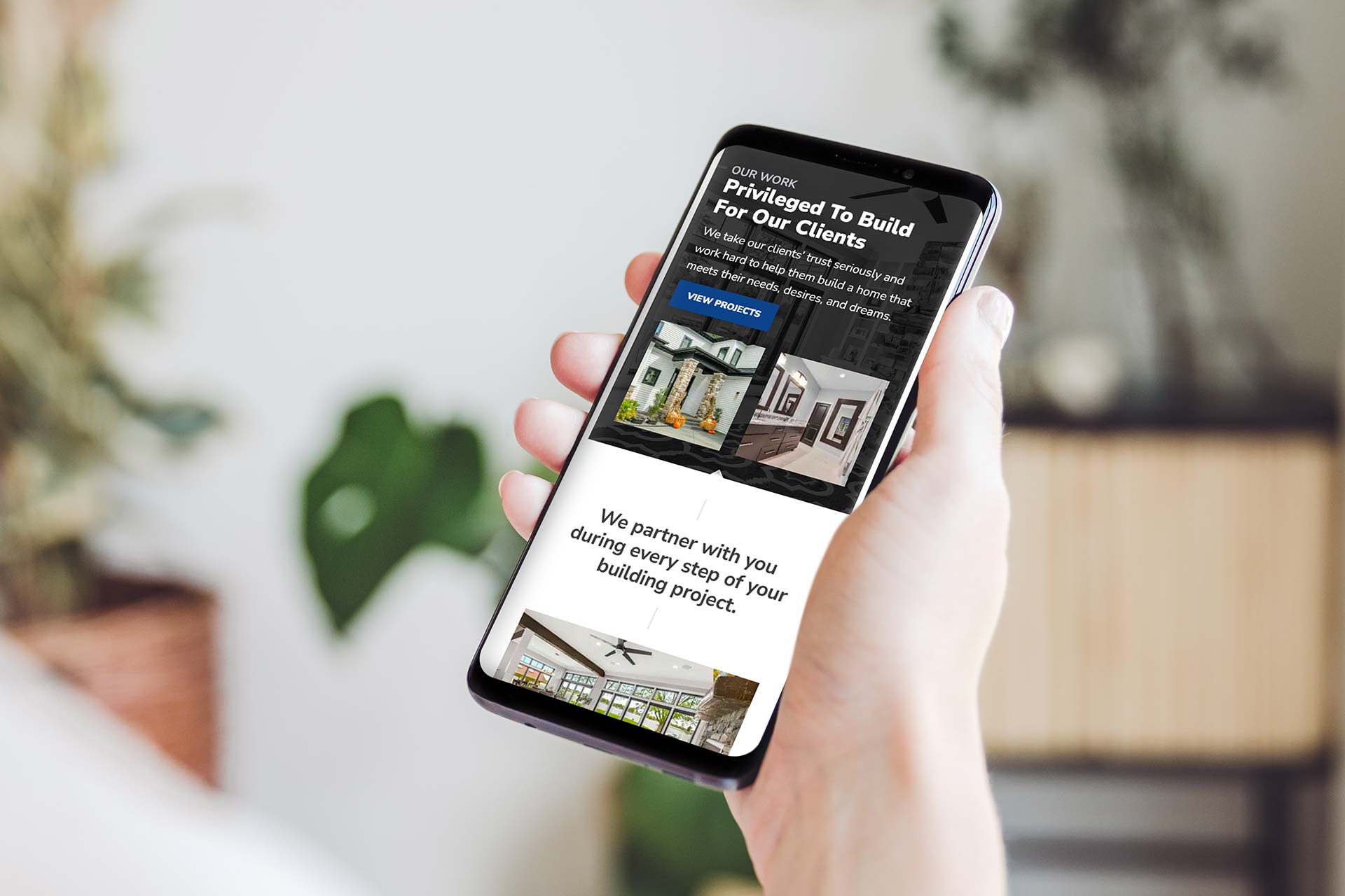 Person with a smartphone displaying Timber Rocks building design website.