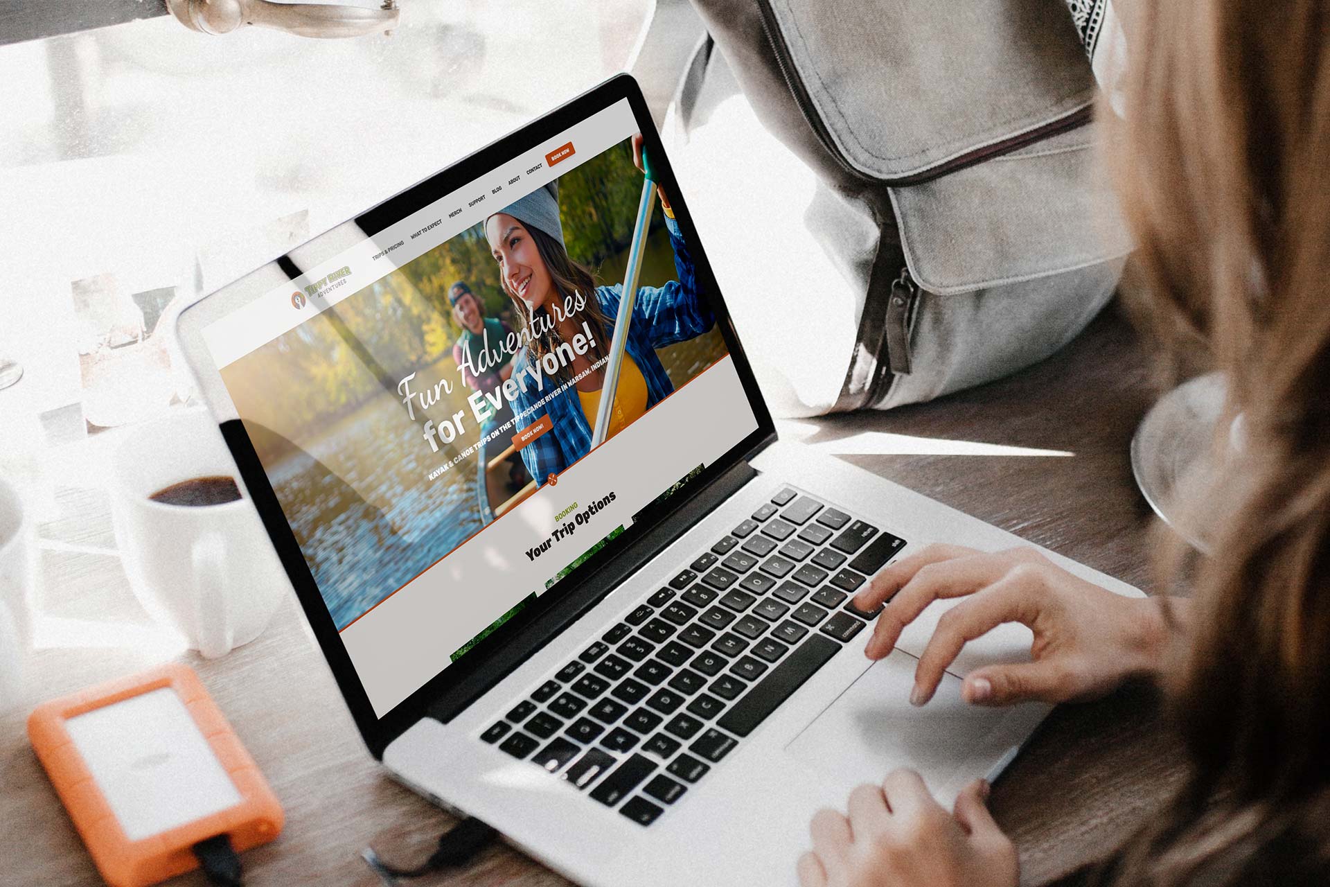 Person using a laptop showing Tippy River adventures website.