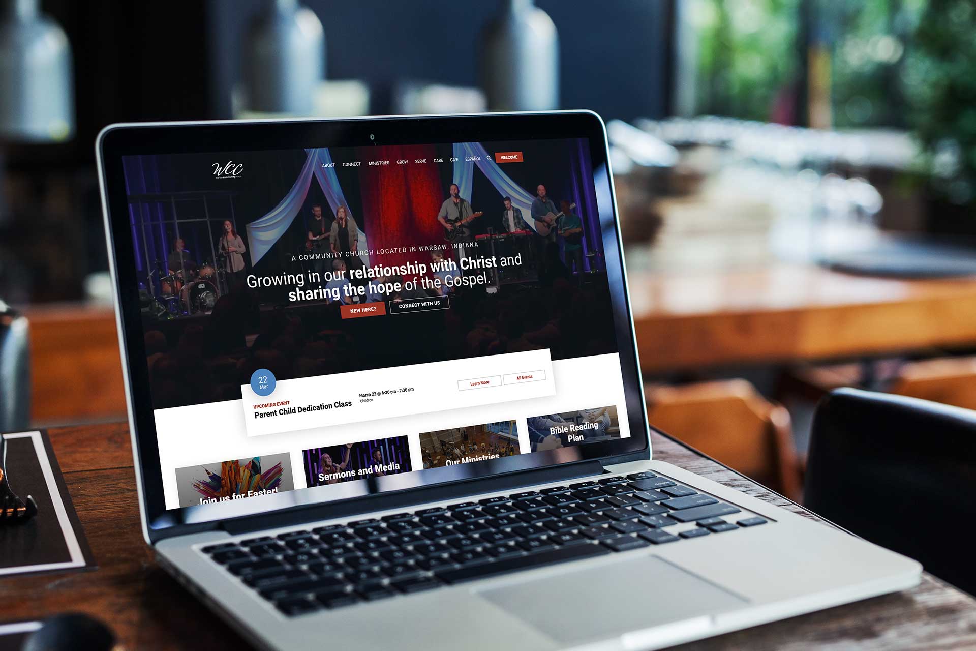 Laptop displaying a church website on a wooden table.